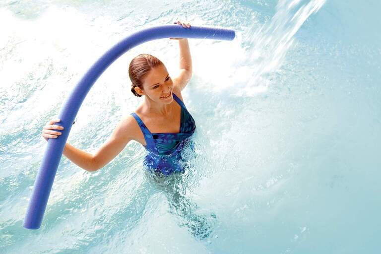 Eine junge Frau macht Wassergymnastik im Pool einer Therme von Bad Füssing.