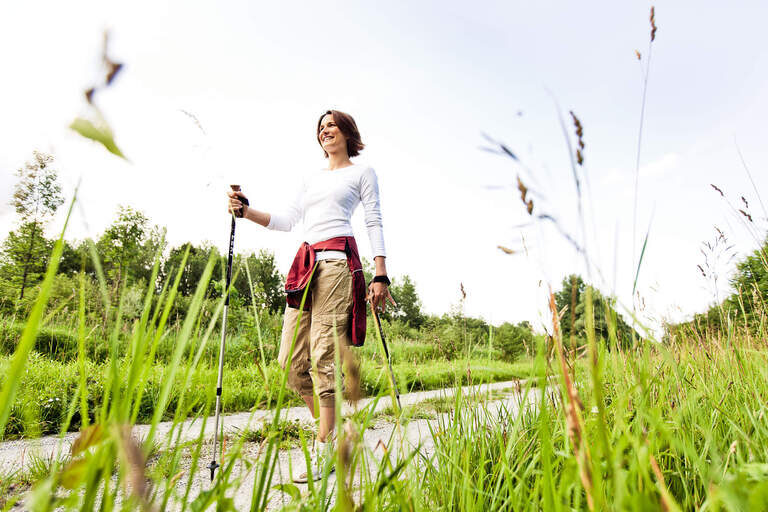 Eine Frau beim Nordic-Walking auf einem sommerlichen Feldweg in Bad Füssing.